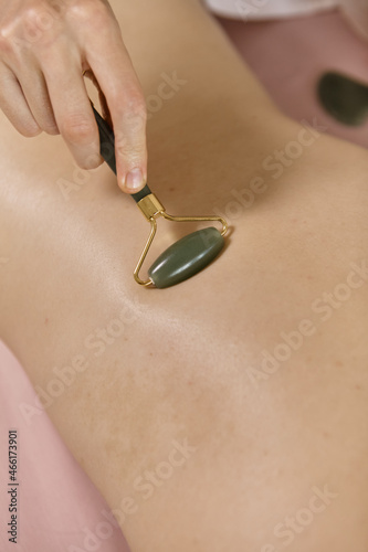 Massage session: woman receiving back Guasha from professional masseur. Attractive caucasian woman having relaxing massage on the back in spa salon. Healthy lifestyle and body care concept