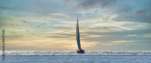 Slika na platnu Sailboat sailing towards the horizon at sunset