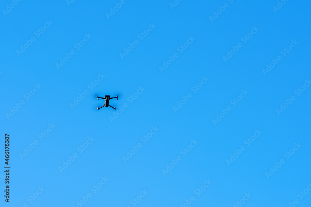 An unmanned quadcopter with a digital camera in the blue sky. An unmanned quadcopter with a digital camera in the blue sky.