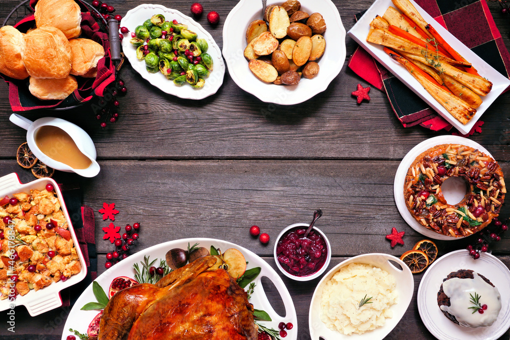 Classic Christmas turkey dinner. Top view frame on a dark wood background. Turkey, potatoes and sides, dressing, fruit cake and plum pudding. Classic Christmas turkey dinner. Top view frame on a dark wood background. Turkey, potatoes and sides, dressing, fruit cake and plum pudding.