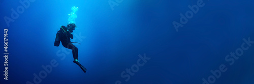 Billede på lærred Background banner with a scuba diver woman standing still in deep blue
