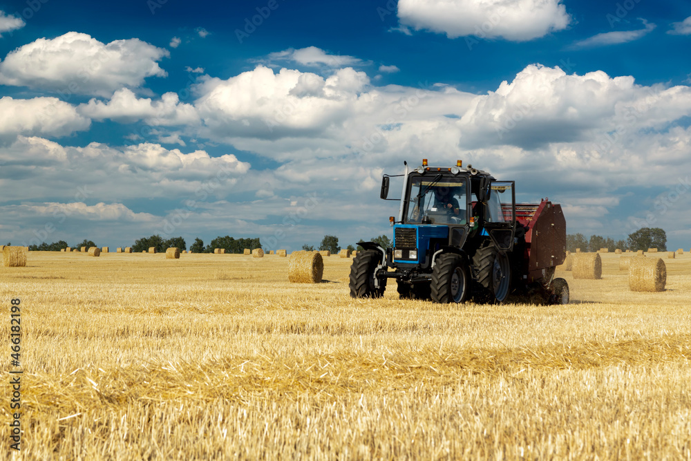 Tractor with bale machine for harvesting straw in the field and making large round bales. Agricultural work, harvesting hay on the hills in summer field Tractor with bale machine for harvesting straw in the field and making large round bales. Agricultural work, harvesting hay on the hills in summer field