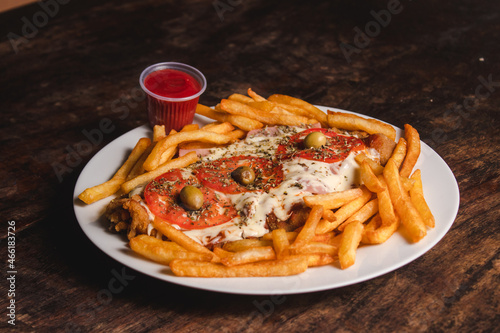 Neapolitan Milanese with french fries on a plate on a wooden table.