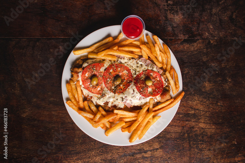 Vászonkép Overhead view of a Neapolitan-style milanesa with french fries on a plate on a wooden table