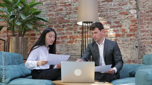 Asian manager consultant broker consults a male client with a laptop demonstrating an online presentation, explains the details of the transaction, convincingly buys services photo
