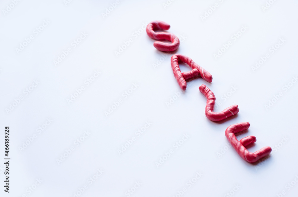 the word sale is made of red plasticine with white flecks on a white background, written diagonally with space for the text and blurred extreme letters the word sale is made of red plasticine with white flecks on a white background, written diagonally with space for the text and blurred extreme letters