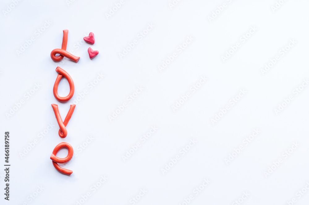 the word love consists of letters made of orange plasticine arranged vertically on a white background with pink hearts on the edges of plasticine the word love consists of letters made of orange plasticine arranged vertically on a white background with pink hearts on the edges of plasticine