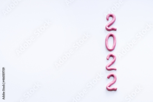 the numbers 2022 are made of pink plasticine, arranged vertically with a place for text on a white background