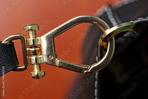 yellow metal latch with a ring on a black leather bag on a red background