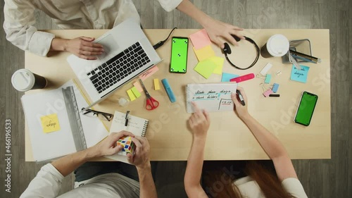 Business people working in modern office together top view. Creative workers discussing tasks. Project planning, group brainstorming. Team leader in headphones typing on laptop keyboard. photo