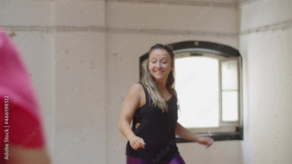 Front view of female instructor dancing in front of group. Medium shot of happy teacher showing movement to senior people in dancing room, rehearsing and communicating. Occupation, sport concept Front view of female instructor dancing in front of group. Medium shot of happy teacher showing movement to senior people in dancing room, rehearsing and communicating. Occupation, sport concept