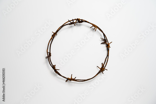 Contemporary Crown of Thorns or Good Friday concept: A wreath of rusted barbed wire against white background. Table top view, flat lay, copy space.