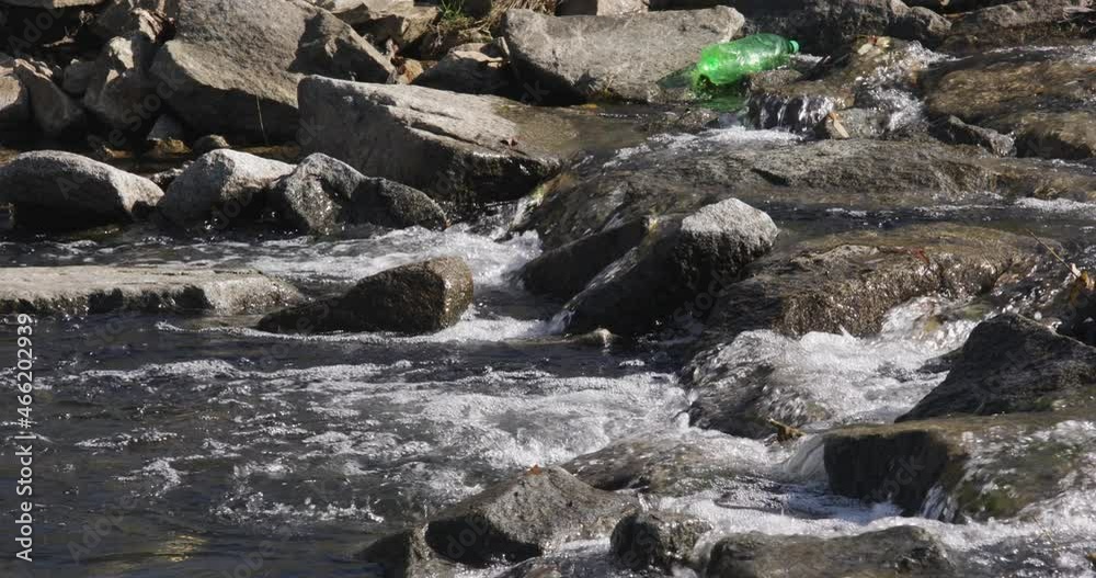 Water pollution - Plastic bottle thrown into small river Water pollution - Plastic bottle thrown into small river