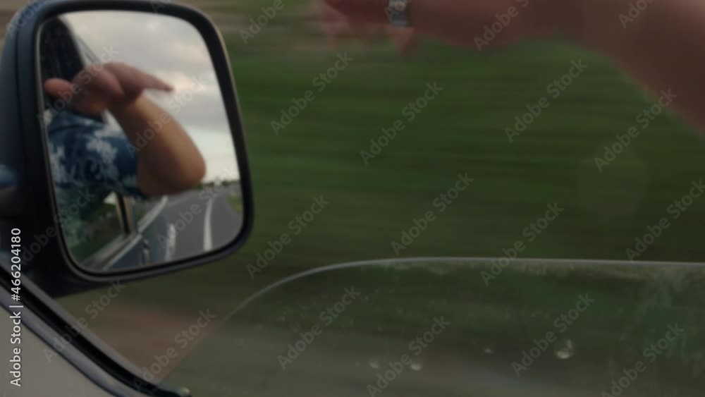 Young man travelling by car or camper van moves hand in wind Young man travelling by car or camper van moves hand in wind
