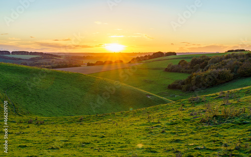 dramatic golden sky, minimal cloud on the horizon as the corona sunsets over a deep green grass valley, Pewsey Vale, North Wessex Downs AONB UK photo