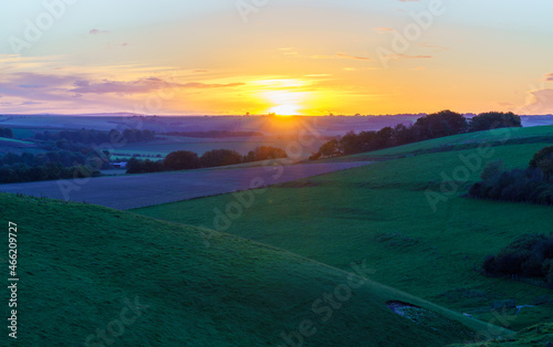 dramatic golden sky, minimal cloud on the horizon as the sunsets over a deep green grass valley, Pewsey Vale, North Wessex Downs AONB UK photo