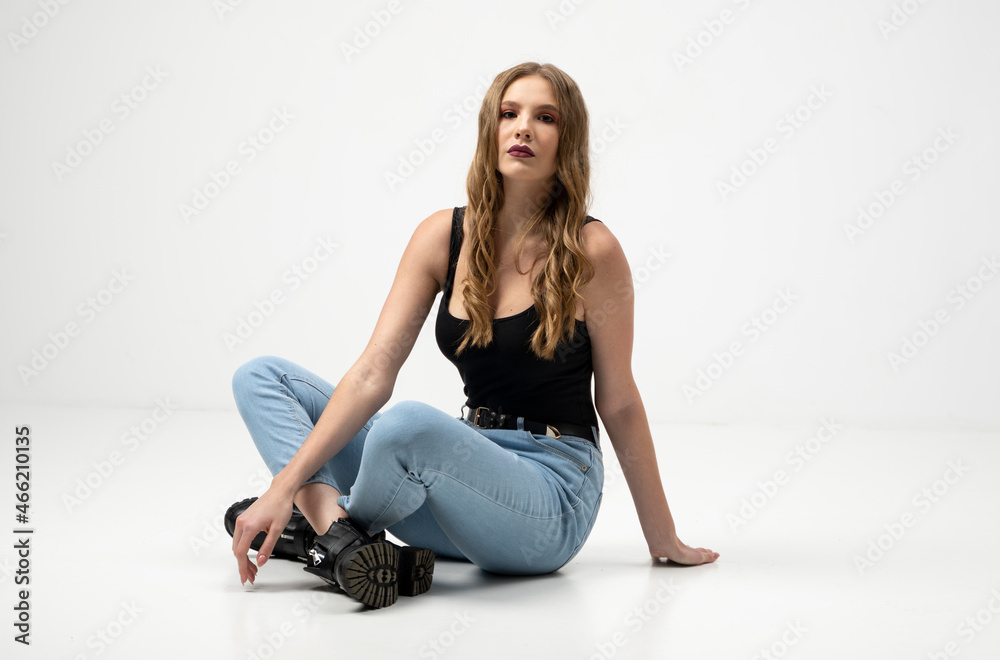 Beautiful young woman portrait in a black t-shirt and blue jeans. Studio shot, isolated on gray background. Beautiful young woman portrait in a black t-shirt and blue jeans. Studio shot, isolated on gray background.