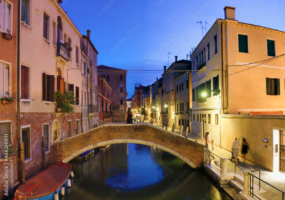 woman standing on a canal bridge in venice at dawn in summer