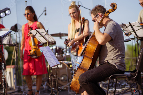 Male musician playing cello in orchestra at outdoor concert