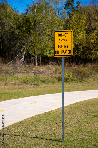 Paved Path Behind a Yellow High Water Warning Sign