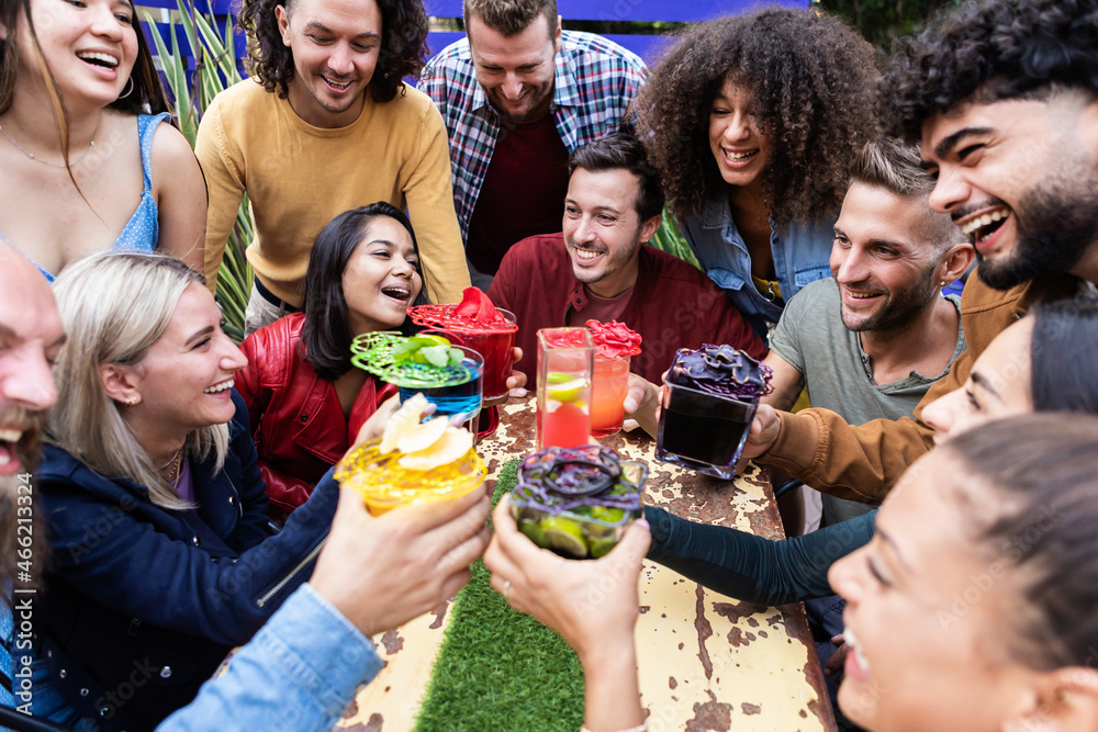 Obraz premium Group party of friends cheering with trendy and multicoloured drinks at fashion cocktail bar - Young people gathering and celebrating together - Youth lifestyle concept - Focus on caucasian man