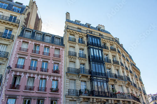 Close, upward exterior view of traditional building architecture in France, with stone walls and beautiful ornate French balconettes