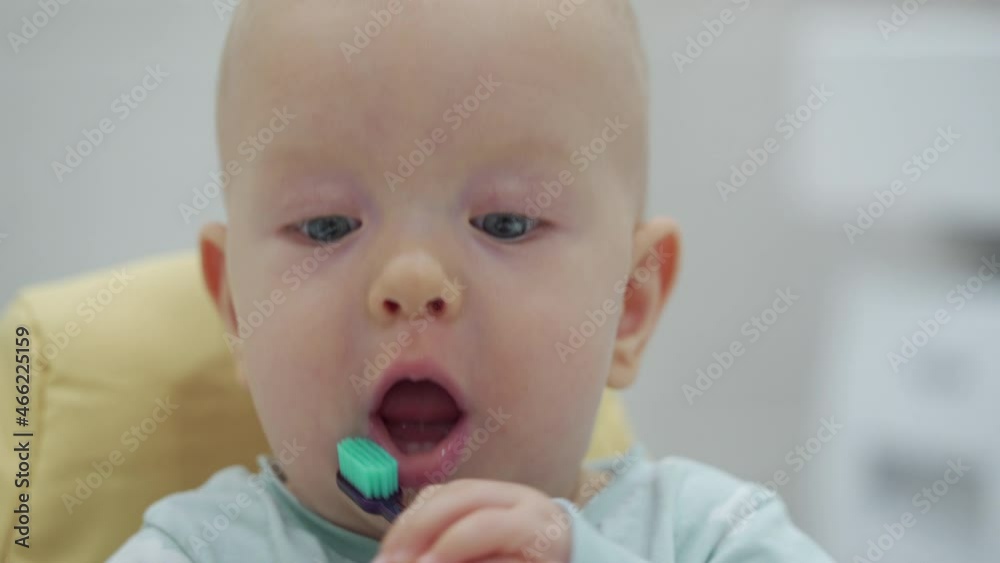 Cute little kid holding a toothbrush, 7 month old baby boy puts a toothbrush in his mouth. High quality 4k footage Cute little kid holding a toothbrush, 7 month old baby boy puts a toothbrush in his mouth. High quality 4k footage