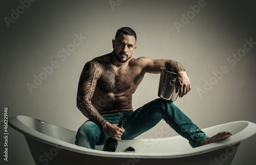 Sexy brutal undress man sit on bathtub in bathroom, men holiday with champagne. Celebrating christmas or birthday. Private sex party.