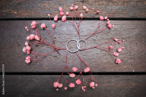 Bilde på lerret Two wedding rings or engagement ring lie on a fern leaf plant on a wooden table,