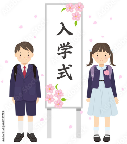入学式の看板の横に立つ新入生の男の子と女の子