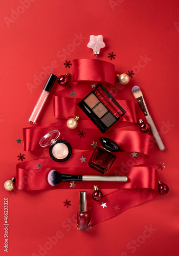 Flat lay composition with makeup products and Christmas decor on red background. Christmas sale of beauty products concept.