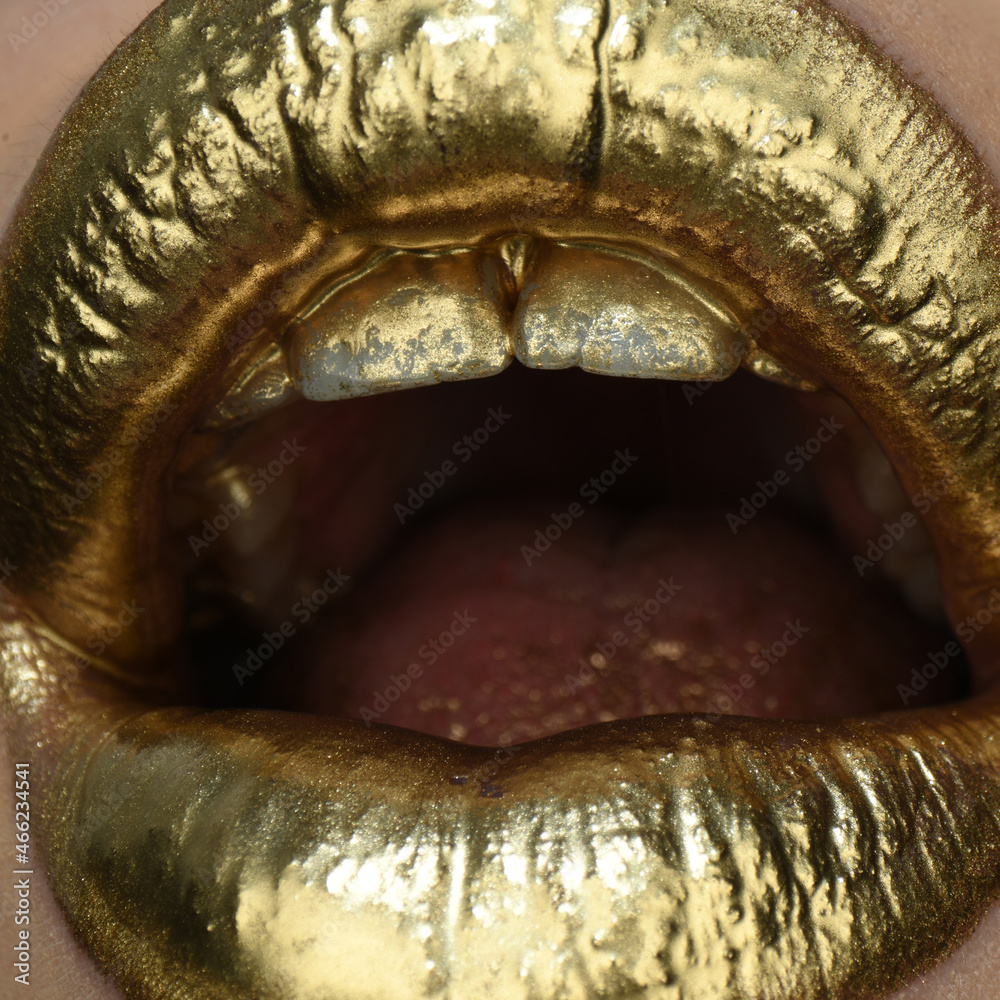 Obraz premium Gold paint on lips. Golden lips, sensual woman mouth. Metallic creative art make up close up. Gold concept. Golden art design.