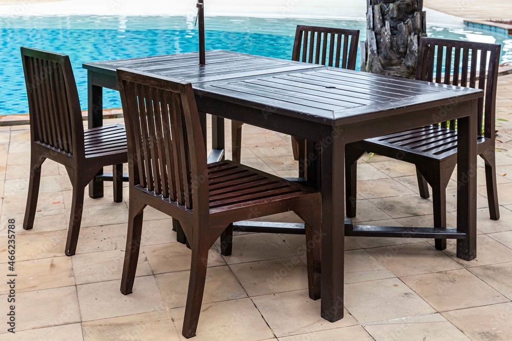 Brown wooden dining table by the pool inside the resort