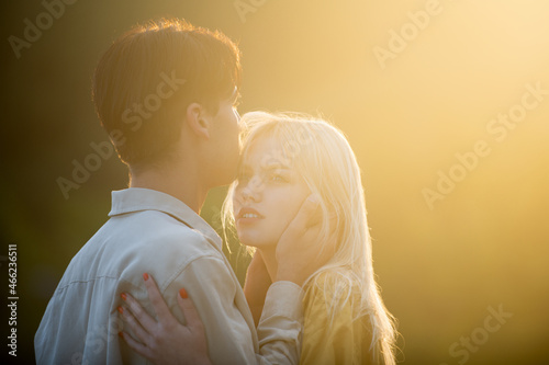 Couple lovers hugging and kissing at sunset. Portrait of lovely couple in love. Young sensual girlfriend glad to passionate kiss from her boyfriend. Handsome young man embraces his woman and kisses.