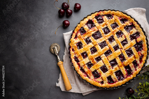 Delicious homemade classic cherry pie with a flaky crust on dark gray background, top view