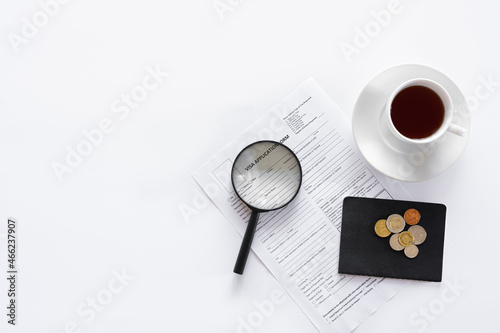 Visa application form, documents and a cup of coffee on a white background.