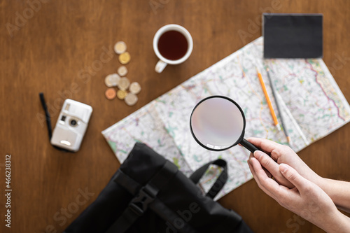 Flat lay, travel planning, trip, map and magnifying glass in female hands.