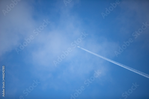 condensation trail of a plane in the blue sky, clouds
