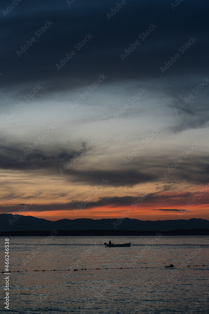 A fisherman's boat in the afterglow over the Croatian coast. A summer scene. A fisherman's boat in the afterglow over the Croatian coast. A summer scene.