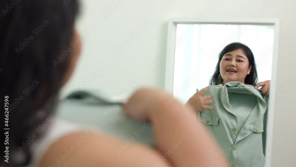 Body positive plus size female clothing. Body positive plus size woman happily and is proud of herself looking at mirror at home Body positive plus size female clothing. Body positive plus size woman happily and is proud of herself looking at mirror at home