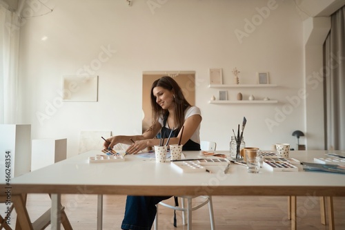 Beautiful Female Artist In Her Studio. Female drawing in album with watercolor paints and paintbrush
