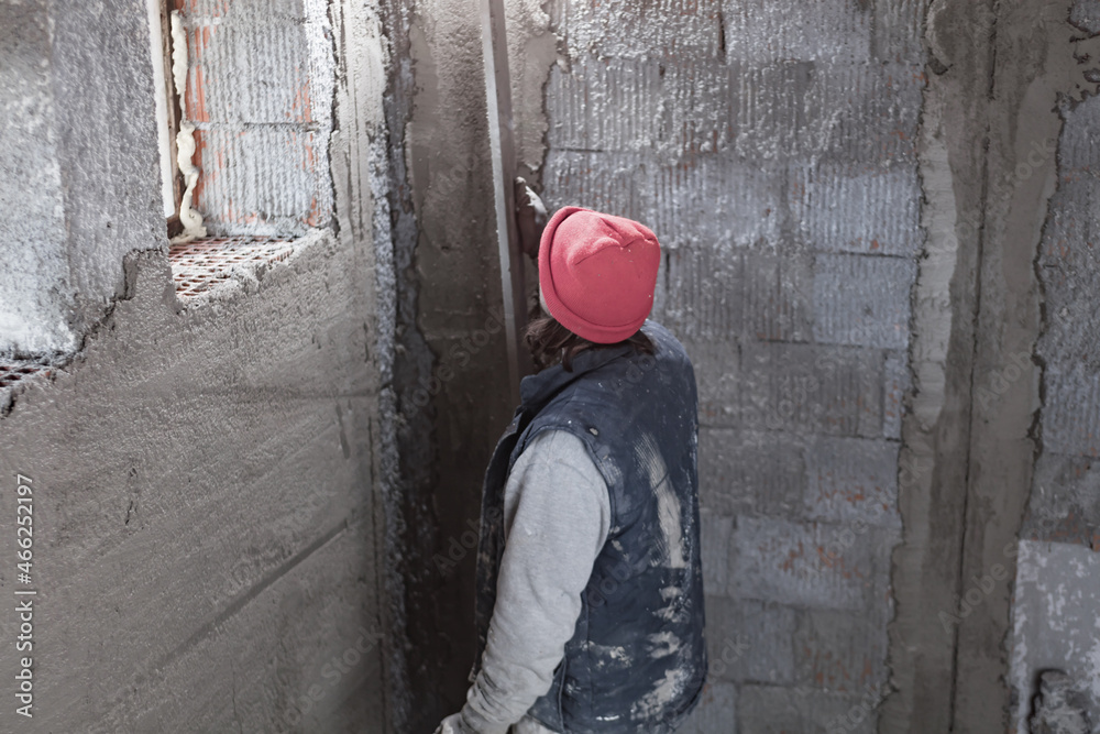 Real construction worker working on a wall inside the new house. Real construction worker working on a wall inside the new house.