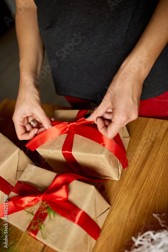 Hands of cropped unrecognisable woman packing Christmas present