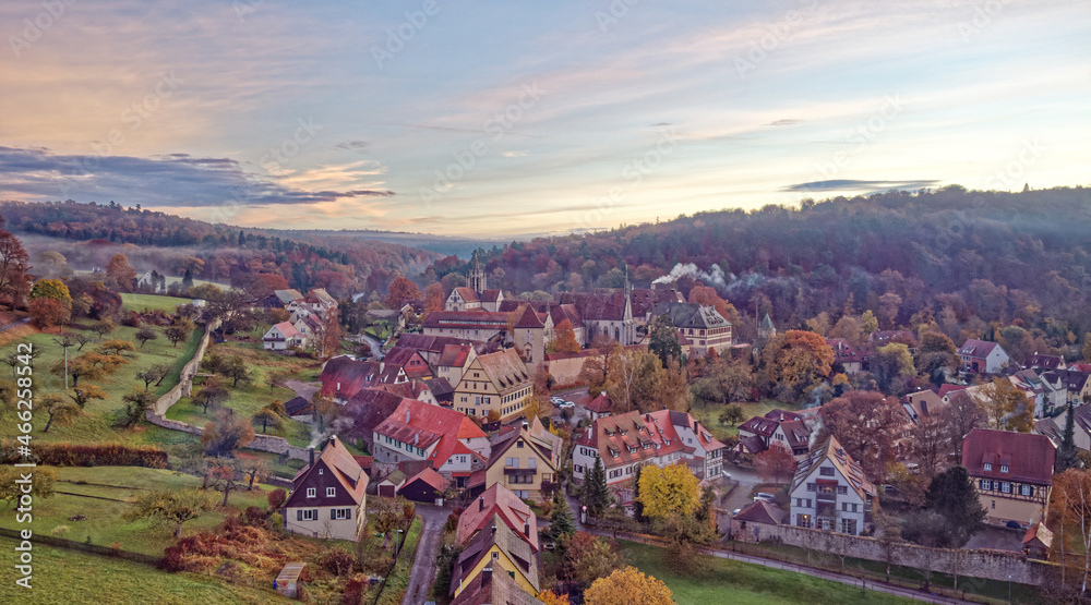 Kleiner Ort mit Klosteranlage im Morgennebel aus der Luft