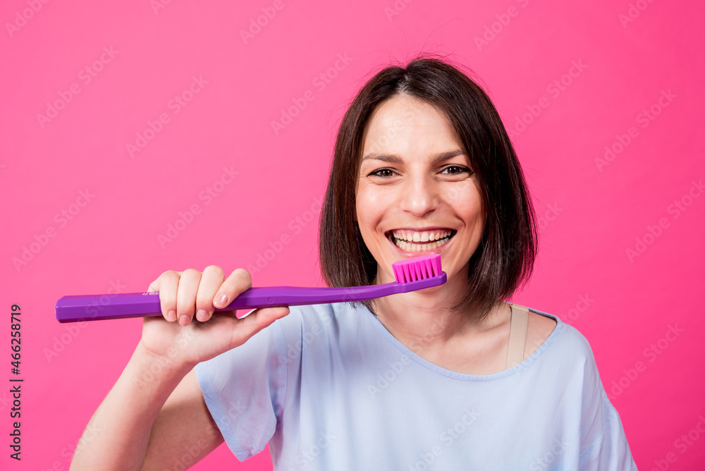 Beautiful happy young woman with big toothbrush on blank pink background Beautiful happy young woman with big toothbrush on blank pink background