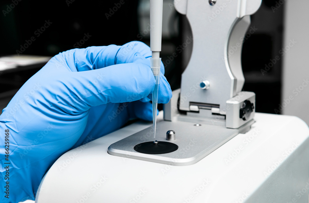 Scientist holds micropipette and loads sample onto low pedestal of