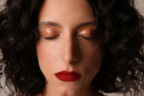 Close-up of young woman with closed eyes make-up. Glossy eyes, red lips. 