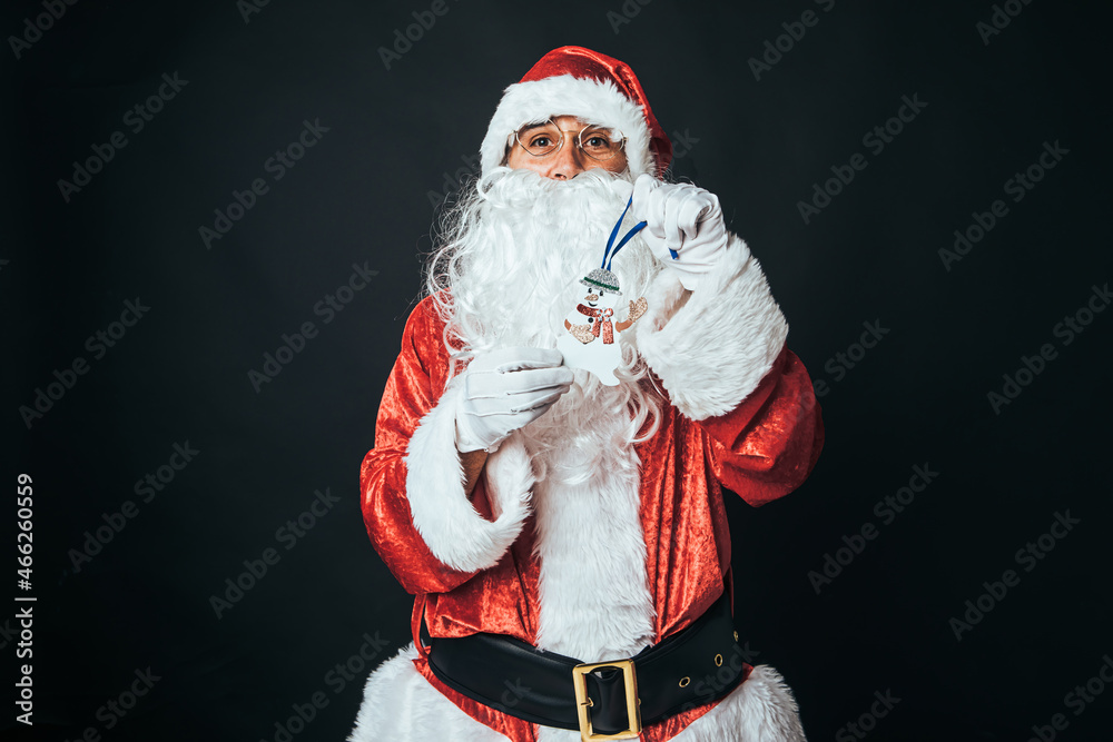 Man dressed as Santa Claus holding the figure of a snowman, on black background. Concept of Christmas, Santa Claus, gifts, celebration. Man dressed as Santa Claus holding the figure of a snowman, on black background. Concept of Christmas, Santa Claus, gifts, celebration.