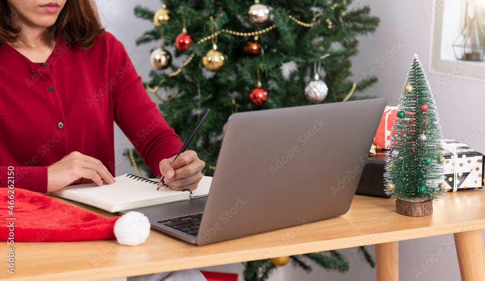 business woman working on computer in Christmas day with gift box and christmas tree background. business woman working on computer in Christmas day with gift box and christmas tree background.