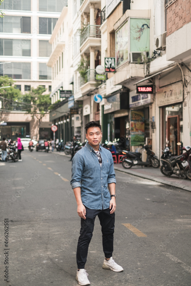 Portrait of asian young handsome man in denim shirt standing on the street and looking at camera with copy space. Chinese people